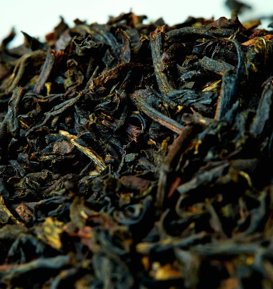Earl Grey black tea leaves scattered on a white tabletop.