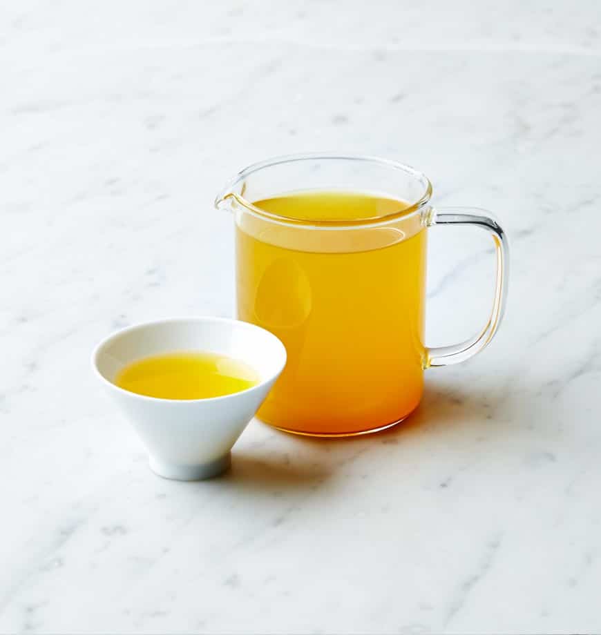 A pitcher and a bowl of tea, accompanied by a label stating Turmeric Spice - Herbal infusion.