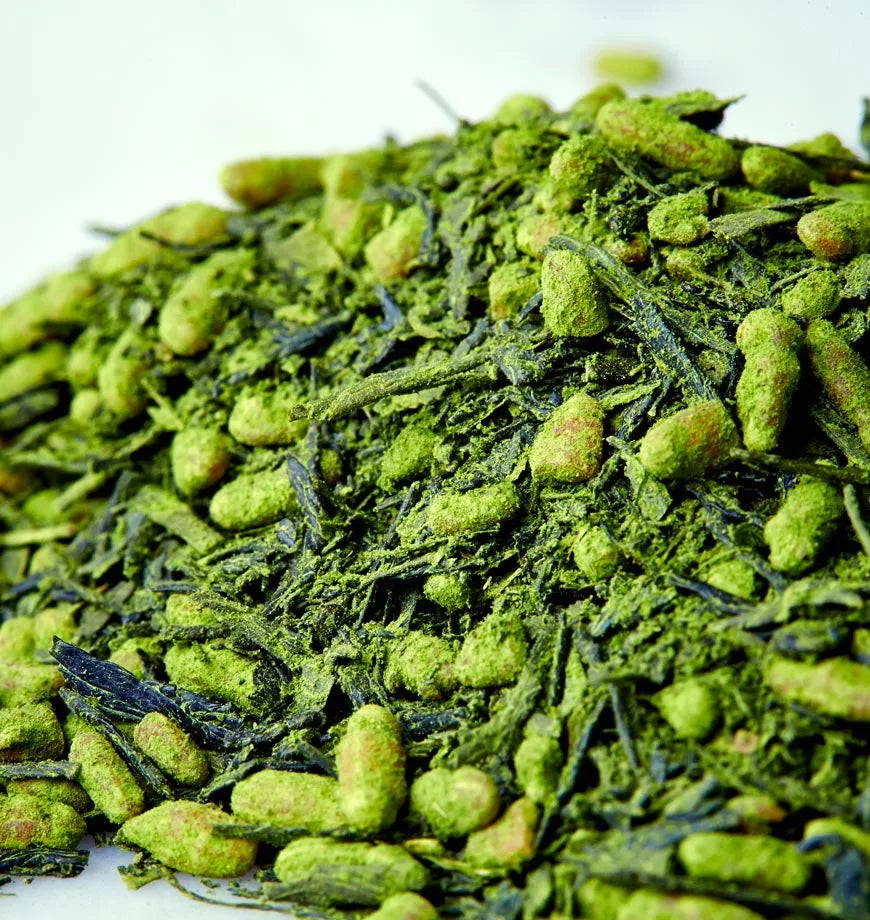 A pile of green tea leaves on a white surface, representing Ryokucha, a traditional Japanese green tea.
