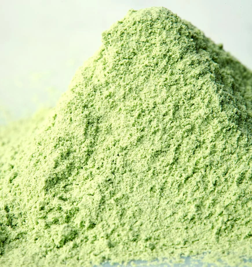 A pile of vibrant green matcha powder on a clean white surface, showcasing its fine texture and rich color.