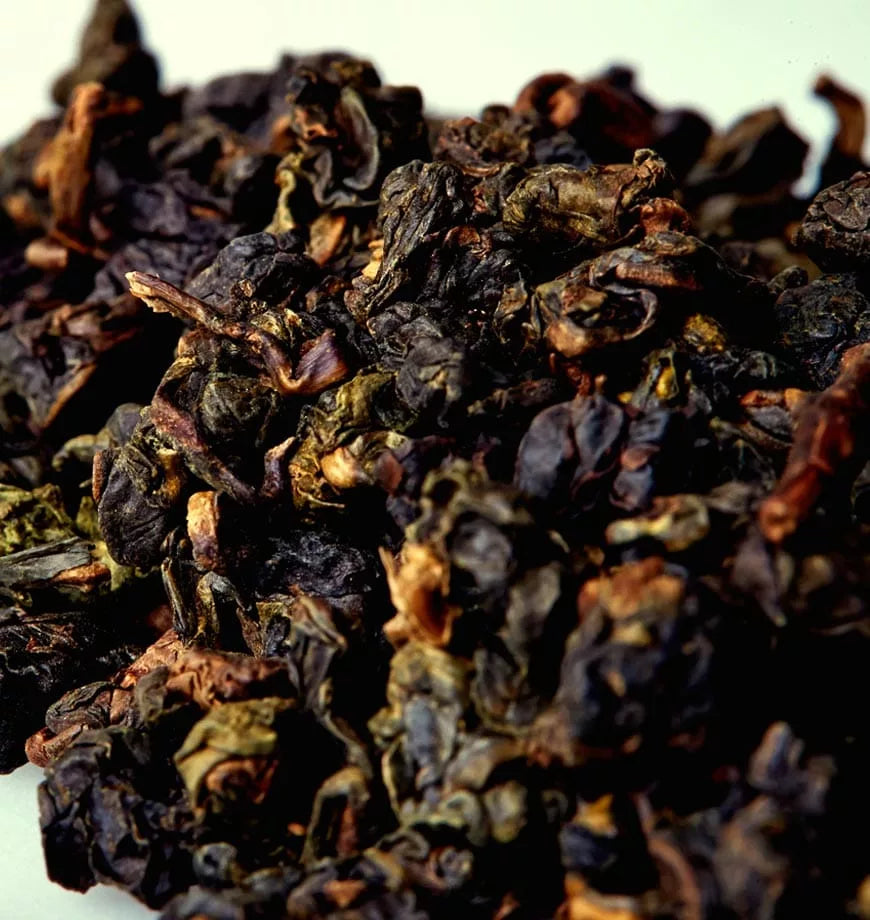 A mound of dried black tea leaves, identified as Oh So Oolong Tea, illustrating the organic oolong tea's deep, rich color.