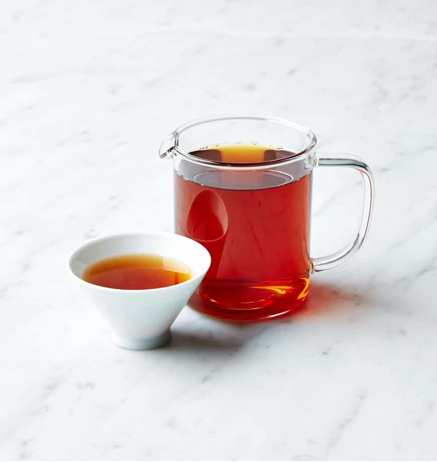 A cup and pitcher of English Breakfast tea displayed on a sleek marble countertop.
