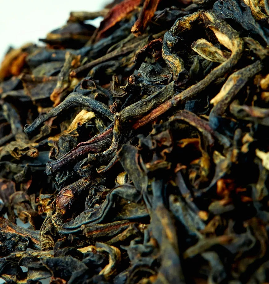 A small mound of English Breakfast black tea, composed of dark black leaves interspersed with lighter brown leaves.