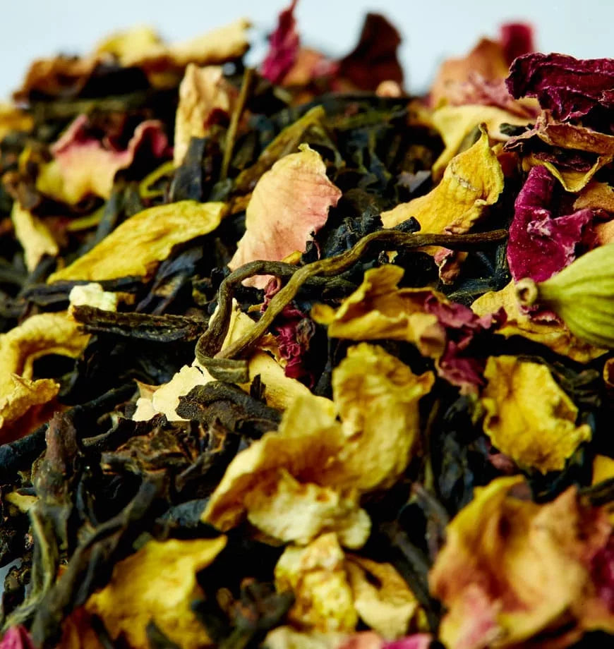 A mound of California Persian tea leaves surrounded by various flowers, emphasizing the beauty of herbal ingredients.