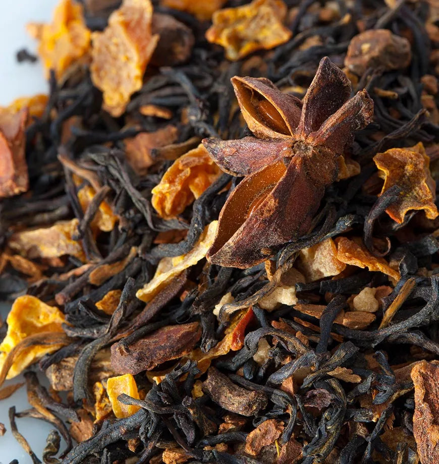 A pile of dried black tea mixed with orange peels and star anise, representing a strong Pumpkin Chai blend.